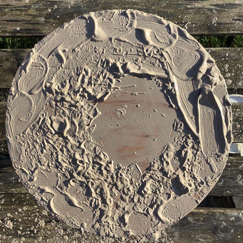 circular board covered in thick pottery slip at ceramic artists jon williams studio near the malvern hills